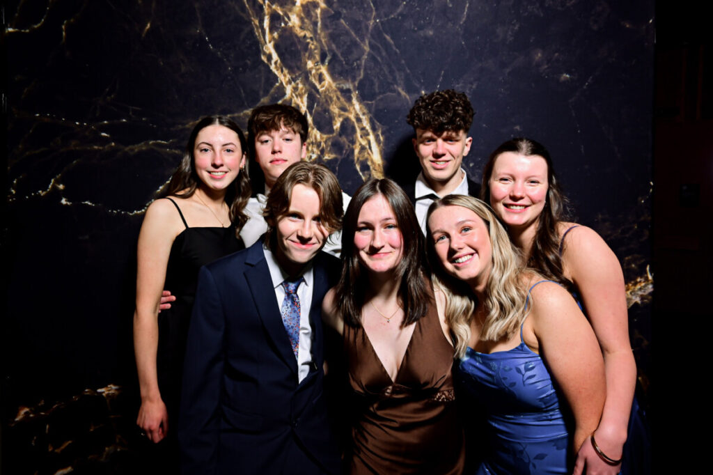 Happy group of friends striking poses against a stylish black matt marble backdrop