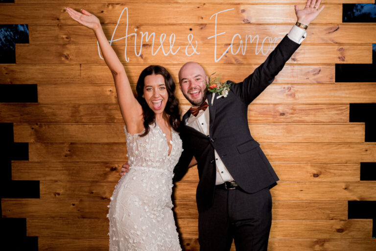 Happy couple posing in front of a wood wall at a Shepparton wedding