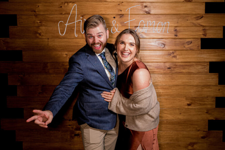 Candid shot of guests laughing and smiling in a wood wall photo booth at a Shepparton wedding